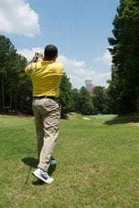 a golfer watching his shot sail towards the green